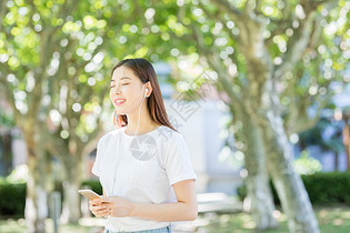 树林下戴耳机听音乐的甜美女生图片