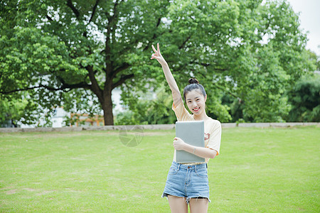 校园草地前女生抱着电脑高清图片