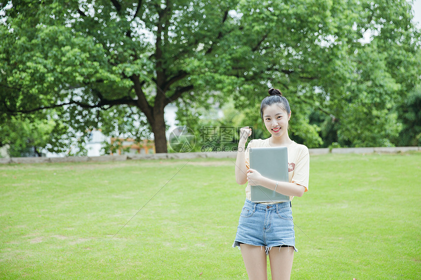 校园草地前女生抱着电脑图片