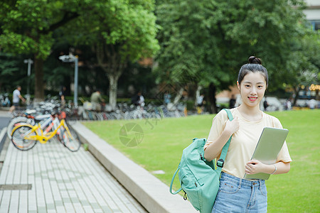 校园草地前女生抱着电脑高清图片