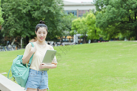 校园草地前女生抱着电脑高清图片