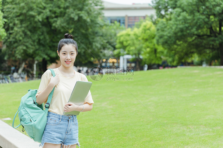 校园草地前女生抱着电脑图片