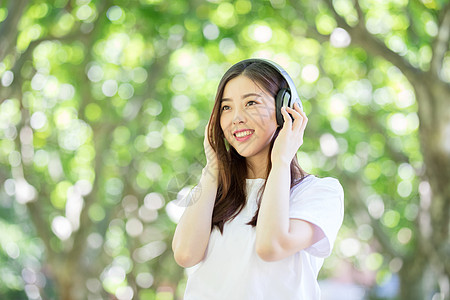 大学生笑脸头戴耳机听音乐的少女背景