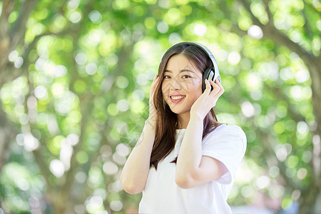 大学生笑脸头戴耳机听音乐的少女背景