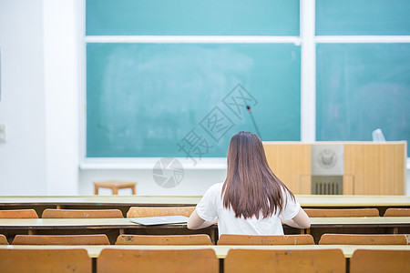 黑板写字空旷的教室里正在学习的女生背影背景