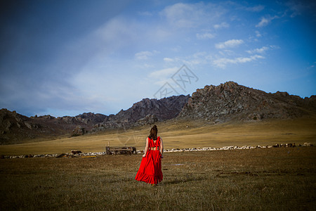 草原上孤独行走的红衣服女孩图片