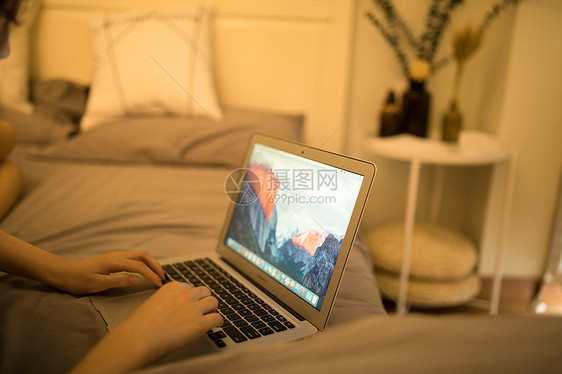躺在床上玩电脑的年轻女性图片