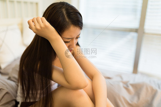 生病头痛坐在床上的女生图片