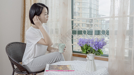 家居窗边女子在窗边手持水杯休息背景