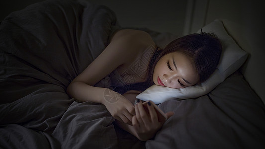 睡眠舱深夜睡前躺着玩手机的女生背景