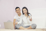 年轻夫妇在卧室用电脑购物图片