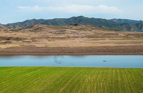 鸭绿江边上的麦田河流山脉背景图片