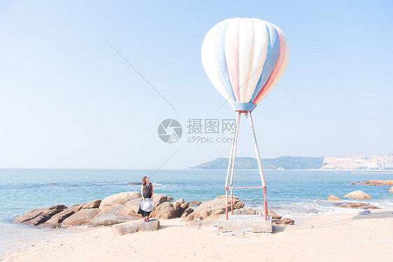 海边热气球旁聆听大海声音的女模特图片