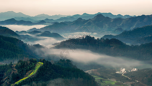 清晨树林晨雾缭绕的群山与小村庄背景