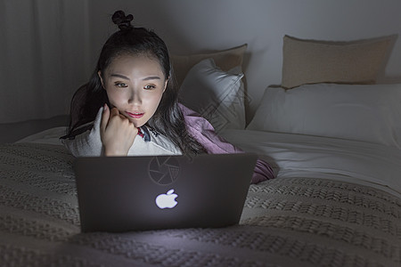 床上玩电脑女子熬夜使用电脑背景