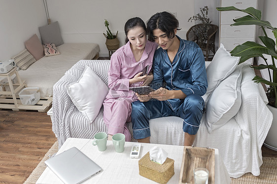 情侣在客厅休息玩手机平板电脑图片