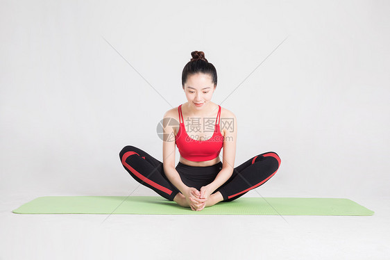 瑜伽垫上做瑜伽动作的年轻女性图片
