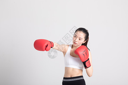 健身房美女戴着拳击手套打拳出拳的年轻运动女性背景