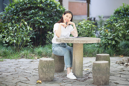 老年学习校园里坐在石凳上读书写字的女生背景