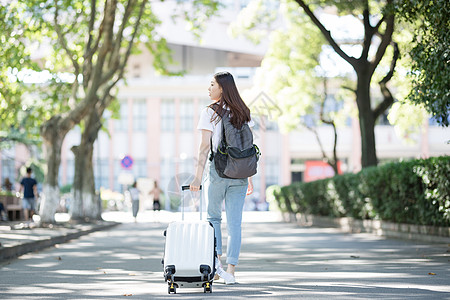 旅行拉杆箱拉着行李箱的女生背影背景