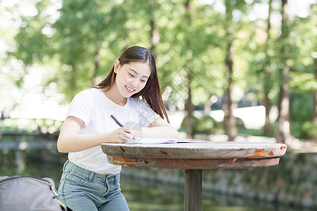 在公园里户外写作业的女同学背景图片