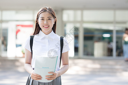 站在教学楼前微笑的额女同学背景图片