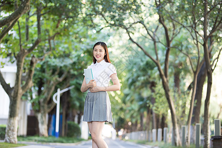 抱着书的学生拿着课本准备去上课的大学生背景