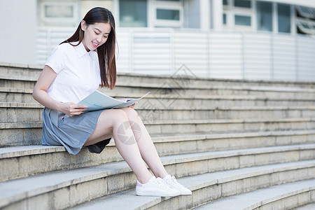 坐在学校台阶上看书的女同学背景图片