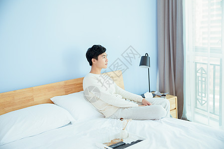 卧室里坐在床边的年轻男性图片