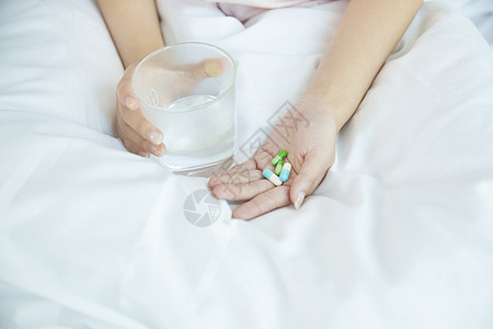 在床上吃药的女性手部特写高清图片