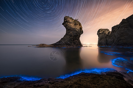 星轨礁石荧光海背景图片