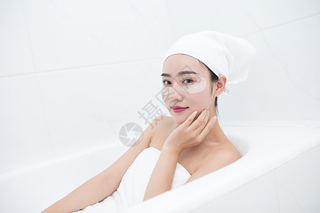 包着头发坐在浴缸里敷眼膜的年轻美女图片