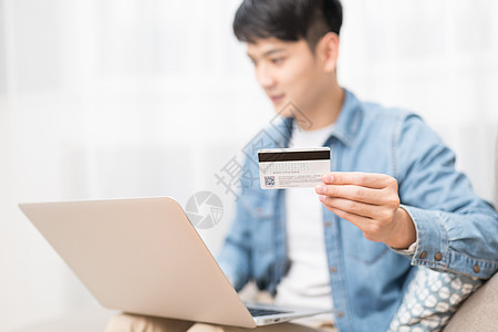 家居男子使用电脑手拿银行卡特写图片