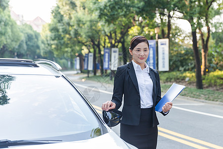 车旁手拿文件夹的商务女士图片