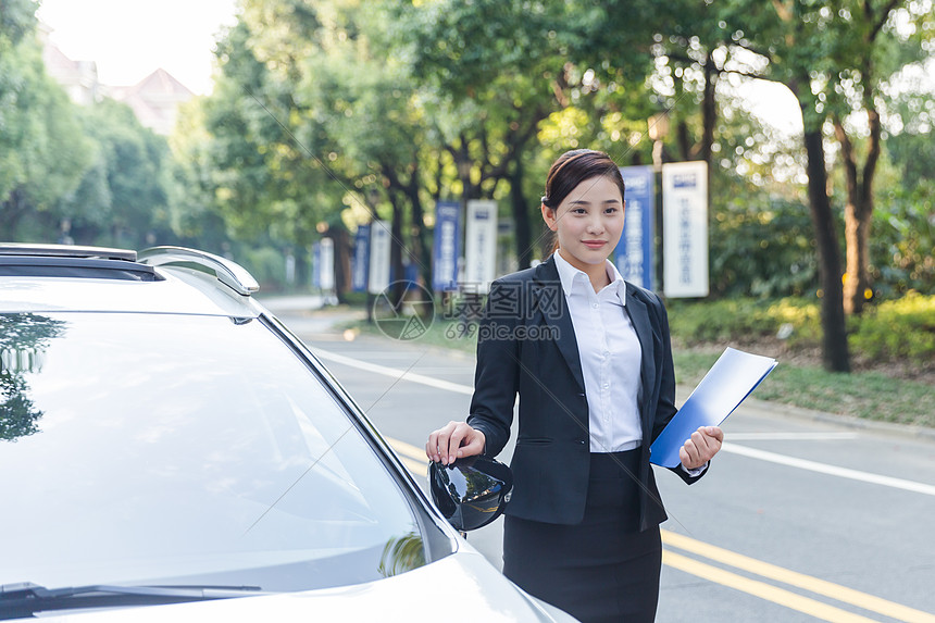 车旁手拿文件夹的商务女士图片