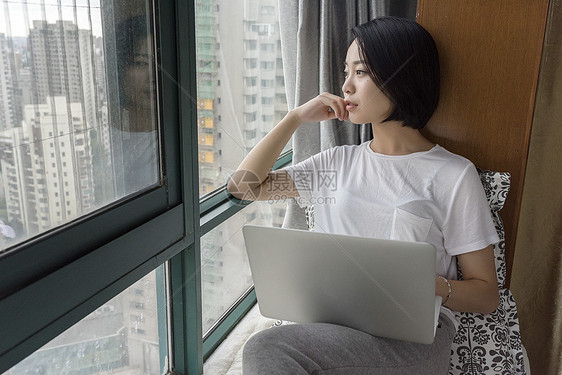 女子坐在飘窗使用电脑图片