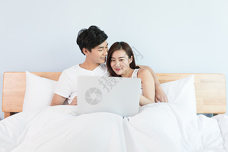 躺在床上看电脑的年轻情侣图片