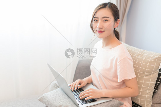 坐在沙发上玩电脑的年轻女性图片