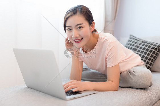 坐在沙发上玩电脑的年轻女性图片