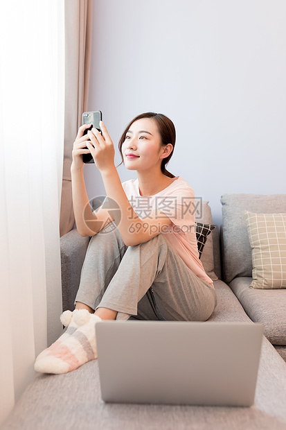 家居女性坐在沙发上玩手机图片