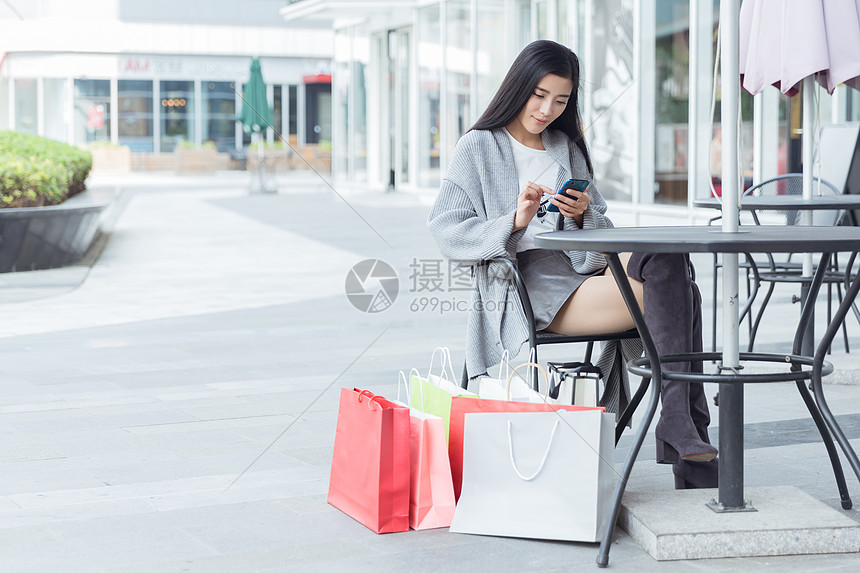 年轻美女购物休息看手机图片