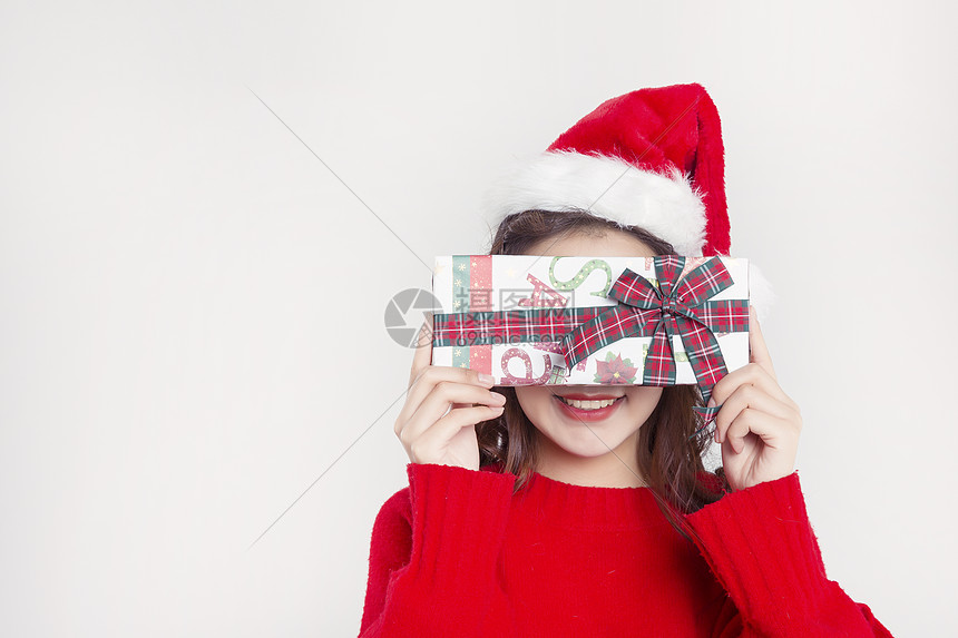 手拿礼物盒的圣诞装扮女性棚拍图片
