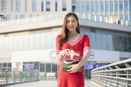 手拿礼物盒的红衣女性背景图片
