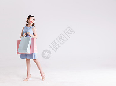 购物袋图标惊喜的拿着购物袋的年轻女性背景