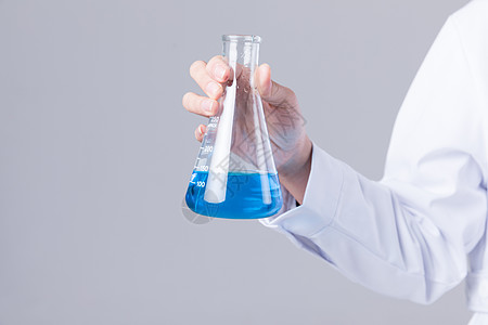 女科学家手拿烧杯观察蓝色液体背景图片