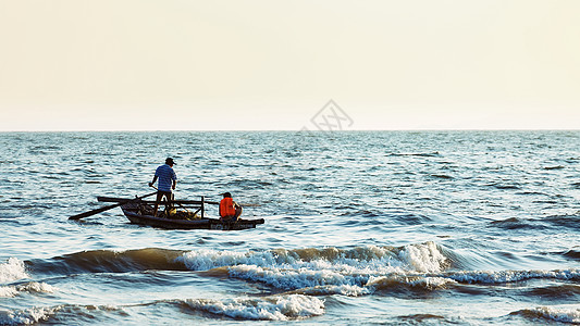 夕阳下海边辛勤劳动的渔民背景图片