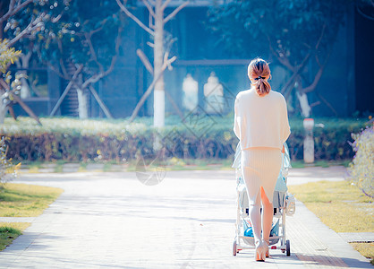 温馨母婴母亲推婴儿车回家背影背景