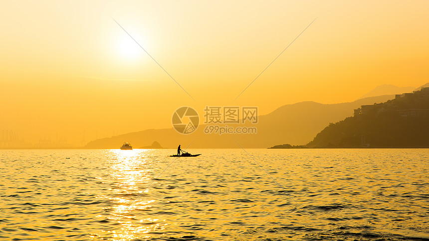 夕阳中海面船只与远山剪影图片