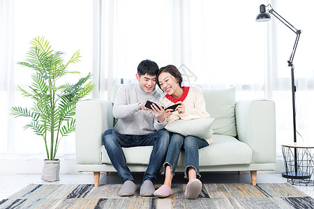 年轻情侣在客厅玩手机游戏背景图片
