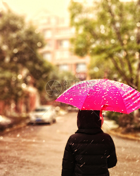 撑着雨伞在雪天中漫步的背影图片